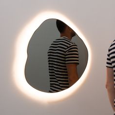 a man standing in front of a mirror with his reflection on the wall behind him