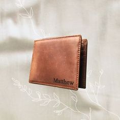 a brown leather wallet sitting on top of a white sheet with the name matthew written on it