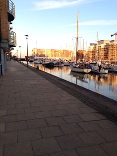 boats are docked in the water next to some buildings and cobblestone walkways