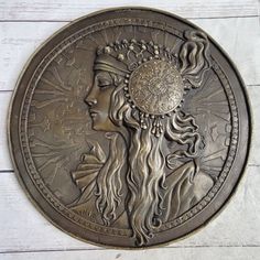 a metal plaque with a woman's head and sun in the center on a white background