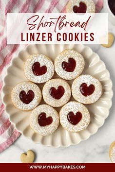 shortbread linzer cookies with jam in the shape of hearts on a white plate