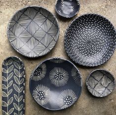 four black and white plates sitting on top of a cement floor next to each other