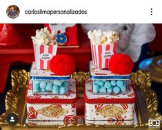 two popcorn boxes with pom - poms on them are sitting on a gold tray