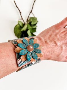 This bracelet is stylish and unique on every level. This feather bracelet features embossing to give it texture and a true feather look. It is cut from an amazing leather backed cork in a bold leopard print with pops of pretty teal. The snap closure is gussied up with a leather flower in teal suede with bronze metallic crackle print and decadent nubuck leather in classic camel. The snap itself is copper tone for a rustic look. The snaps are set about 7.25" apart allowing this to fit an average w Feather Cuff Bracelet, Feather Cuff, Feather Bracelet, Cowgirl Jewelry, Leather Flower, Hippie Bracelets, Festival Jewelry, Coastal Cowgirl, Leather Flowers