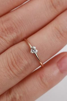 a woman's hand with a diamond ring on top of her finger, showing the middle