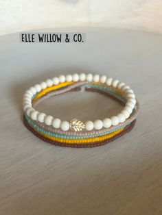 three bracelets with white beads and gold accents on top of a wooden table next to a sign that says, ele willow & co