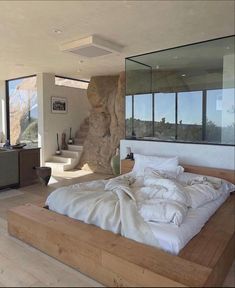 a large bed sitting in the middle of a bedroom next to a wall with windows