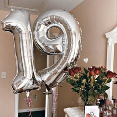 a bouquet of flowers and balloons in the shape of the number twenty nine on a table