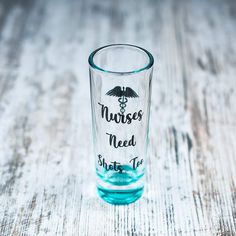 a shot glass with the words nurses need shots in black ink on it, sitting on a wooden table