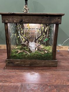 a deer head in a glass case with moss