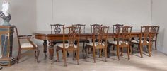 a dining room table with many chairs and a vase on the floor next to it