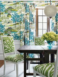 a dining room with blue and green wallpaper, white chairs and a wooden table