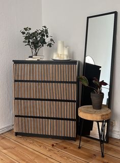 a room with a mirror, table and plant on top of the dresser next to it