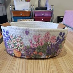 a basket with flowers painted on it sitting on a table