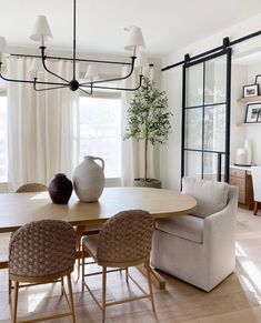 a dining room table with chairs and a vase on top of it in front of a window