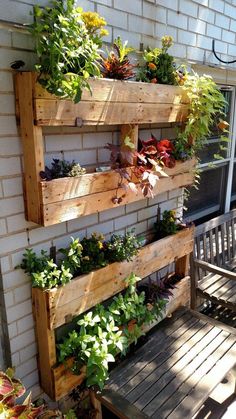 some plants are growing on the side of a building with wooden pallets and benches