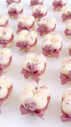 some white chocolates with pink bows and flowers on them are arranged in the shape of hearts