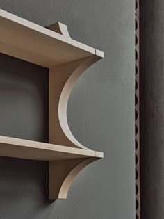 two wooden shelves on the side of a wall, one shelf has a curved edge