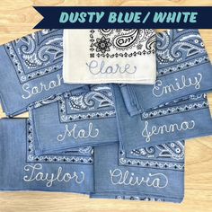 six personalized bandannas with embroidered name and paisley design on them, sitting on a wooden surface