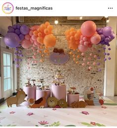 a table topped with lots of balloons next to a wall covered in animals and cats