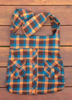 a brown and blue checkered shirt is hanging on a wooden wall with the straps down