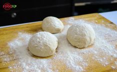 three doughnuts on a wooden cutting board with flour