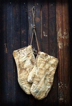 an old pair of oven mitts hanging on a wooden door with rope attached to it