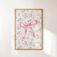 a painting hanging on the wall with a pink ribbon tied to it's bow