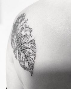 a black and white photo of a leaf on the back of a woman's shoulder