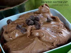 a close up of a cake in a pan with frosting and chocolate chips on top