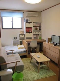 a small living room with a couch, desk and computer on the table in it