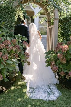 the bride and groom are walking down the path to their wedding ceremony in an archway