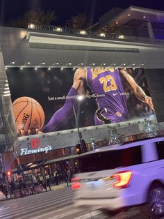 a large billboard on the side of a building with a basketball game in it's center