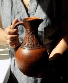 a person holding a wooden vase in their hand