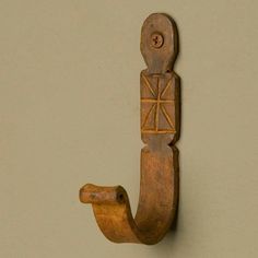 an old wooden hook on the wall with a decorative design hanging from it's side