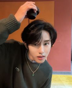 a young man is drying his hair with a blow dryer in front of him