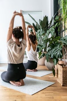 two women doing yoga in front of a potted plant