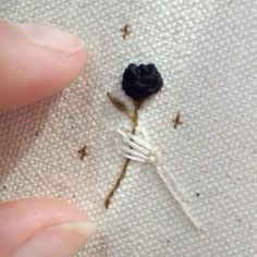 someone is stitching a flower on the back of a white piece of cloth with black thread