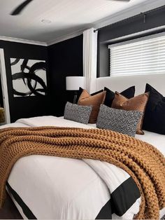 a bedroom with black walls and white bedding has a large braid on the headboard