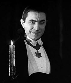 a man in a tuxedo holding a lit candle