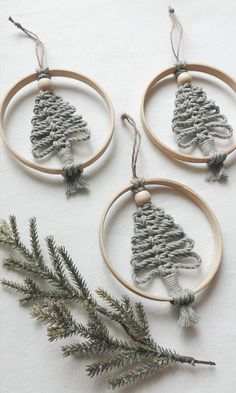 three wooden hoop ornaments with pine cones hanging from the top, and two fir branches on each side