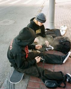 a young man sitting on the ground with his skateboard