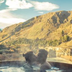 two people in a hot tub with mountains in the background