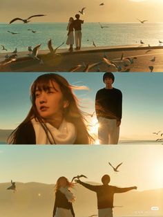 two people standing on the beach with seagulls flying over them and one person holding his arms out