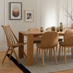 a dining room table with chairs and vases on top of it in front of a white wall