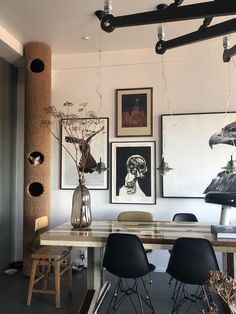 a dining room table with chairs and pictures on the wall above it, along with art