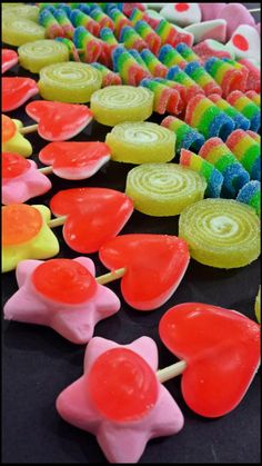 colorful candy lollipops are lined up on a black table with other candies