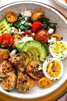 a white bowl filled with different types of vegetables and eggs on top of a table