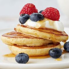 stack of pancakes topped with whipped cream and berries