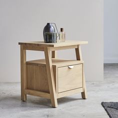 a wooden table with two drawers and a bottle on top, next to a rug